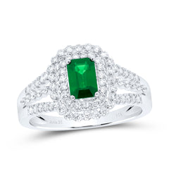 A close-up of a white gold ring featuring an emerald gemstone at the center, surrounded by small, sparkling diamonds.