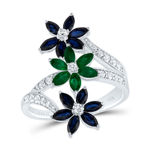 White gold diamond ring with three stacked flower designs, featuring two blue sapphire flowers on the sides and one emerald flower in the center.