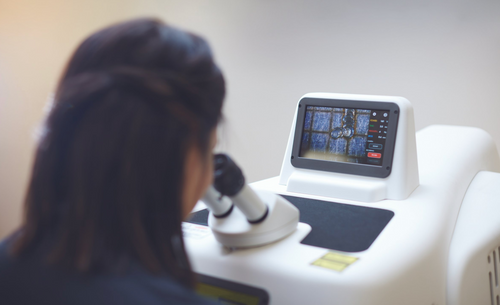 A woman looking into a jewelry laser machine, focusing on the process