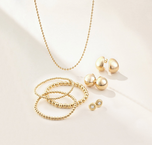 Gold necklaces, earrings, and bangles displayed on a tan background.