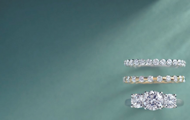 A pair of bezel-set earrings with green, purple, red, and orange stones, displayed on a white background.