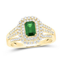 A close-up of a yellow gold ring featuring an emerald gemstone at the center, surrounded by small, sparkling diamonds.