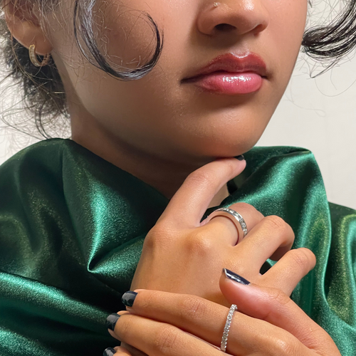 A close-up of a girl's lower profile, with her lips below, wearing a green satin scarf and displaying two diamond rings on her fingers