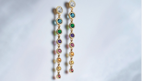 A pair of bezel-set earrings with green, purple, red, and orange stones, displayed on a white background.